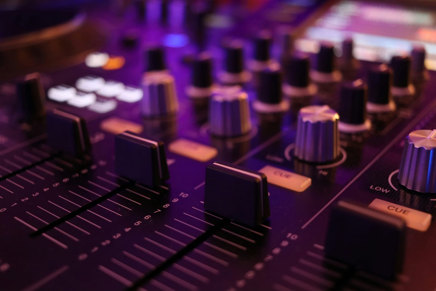 Mikser audio z rzędami tłumików i gałek podświetlony fioletowym światłem